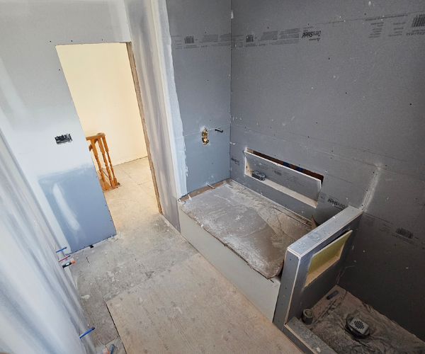 Primary bathroom drywall and tub framing rough-in stage by Noble General Contracting.